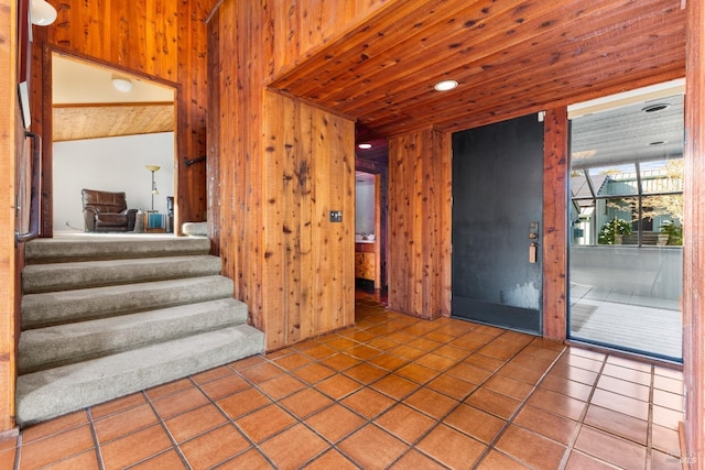 interior space featuring wood ceiling, wood walls, tile patterned flooring, and stairs