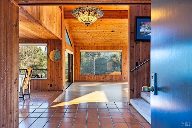 entryway featuring stairway, tile patterned floors, wood walls, and lofted ceiling