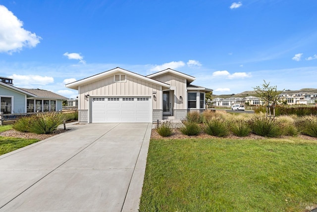 view of front of home featuring driveway, a front yard, board and batten siding, and an attached garage