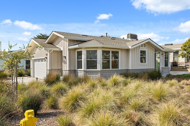 view of home's exterior featuring board and batten siding, an attached garage, central AC, and a shingled roof