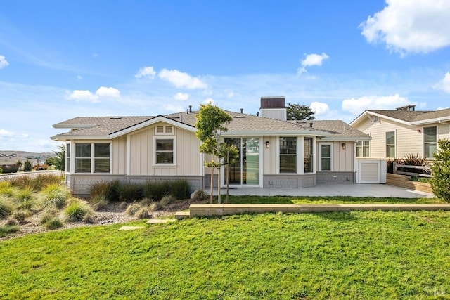 view of front of home featuring a front lawn, board and batten siding, a shingled roof, and a patio