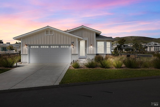 view of front facade with brick siding, board and batten siding, concrete driveway, a garage, and a mountain view