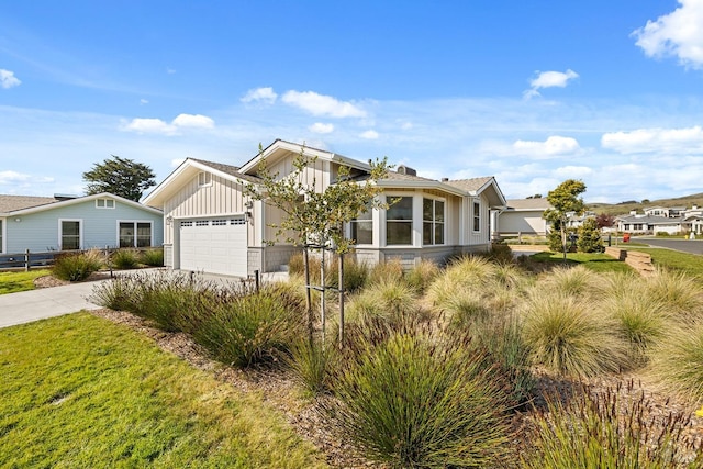 view of front facade featuring board and batten siding, a front yard, driveway, and a garage