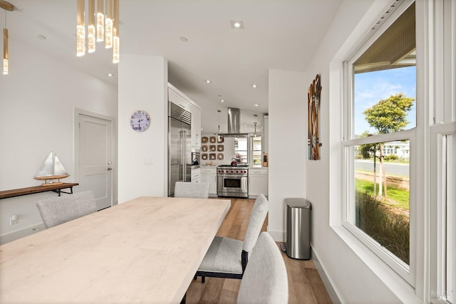 dining room with recessed lighting, baseboards, an inviting chandelier, and light wood-style flooring