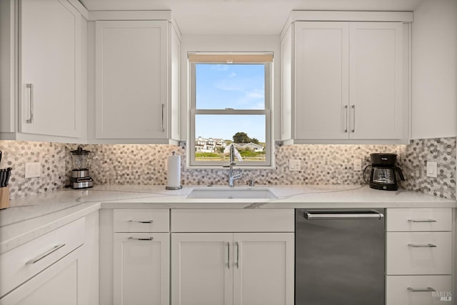 kitchen featuring decorative backsplash, white cabinets, stainless steel dishwasher, and a sink