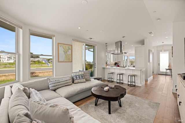 living area with recessed lighting, visible vents, baseboards, and light wood-style flooring