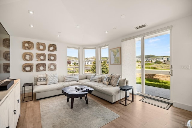 living area with light wood-type flooring, visible vents, baseboards, and recessed lighting