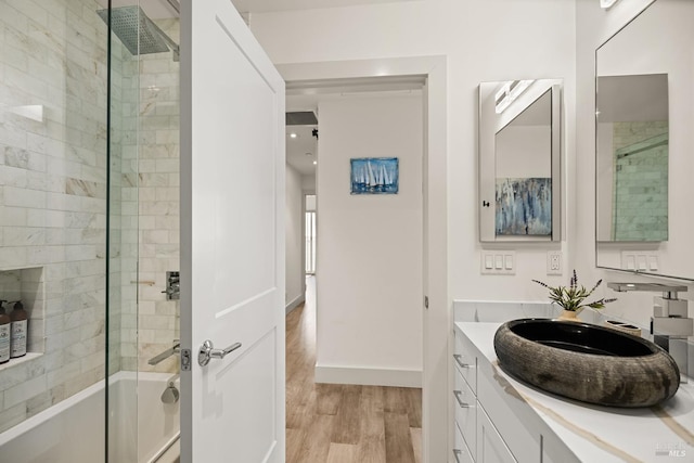 bathroom with baseboards, shower / washtub combination, wood finished floors, and vanity