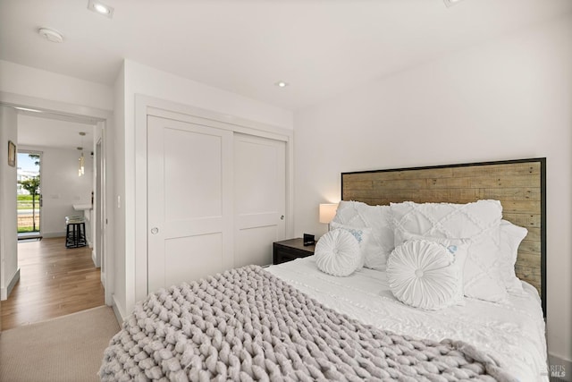 bedroom with a closet, recessed lighting, and wood finished floors