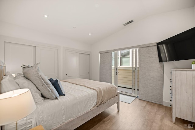 bedroom featuring access to exterior, visible vents, two closets, vaulted ceiling, and light wood-style flooring