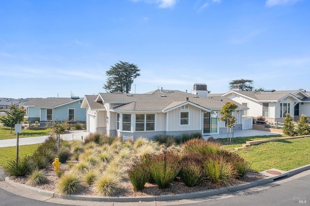 view of front of house with concrete driveway, board and batten siding, a residential view, and a front lawn