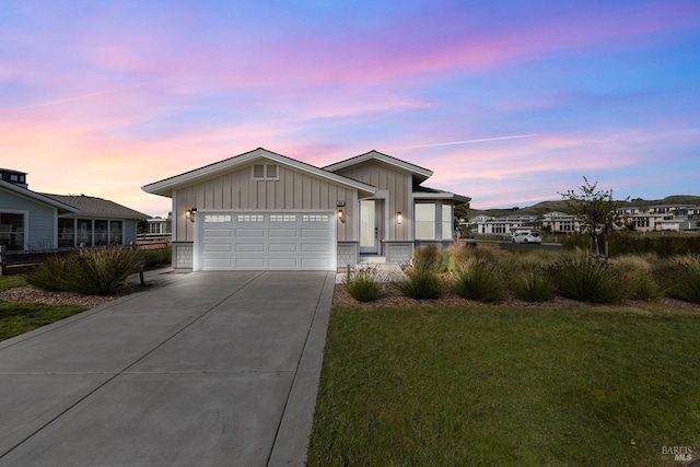 view of front of house with concrete driveway, an attached garage, a lawn, and board and batten siding