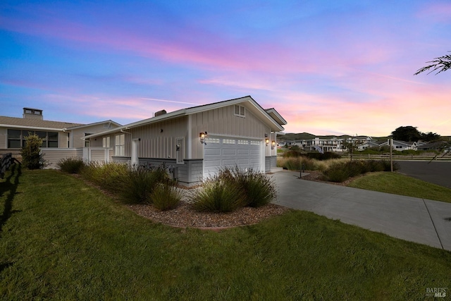 view of front of house featuring a lawn, concrete driveway, and a garage