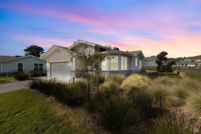 view of front facade with board and batten siding, concrete driveway, a garage, and a front yard