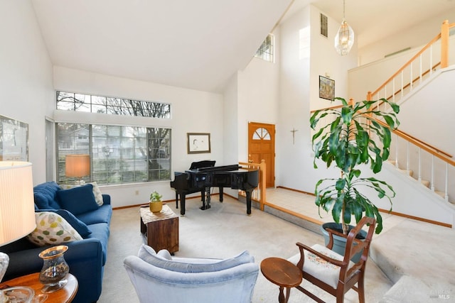 carpeted living area with high vaulted ceiling, visible vents, baseboards, and stairs