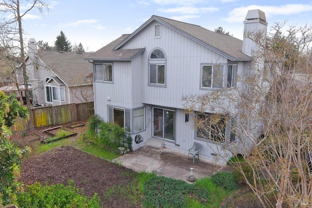 back of property featuring a shingled roof, a chimney, a patio area, and fence