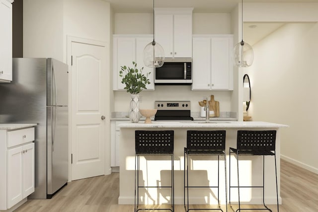 kitchen with a center island with sink, appliances with stainless steel finishes, white cabinetry, a kitchen breakfast bar, and light wood-type flooring