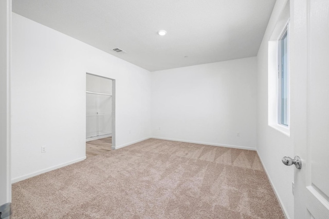 empty room featuring visible vents, light colored carpet, and baseboards