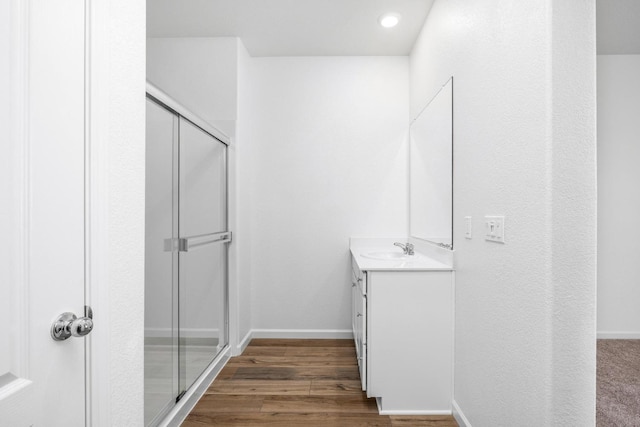 bathroom featuring baseboards, wood finished floors, a stall shower, and vanity