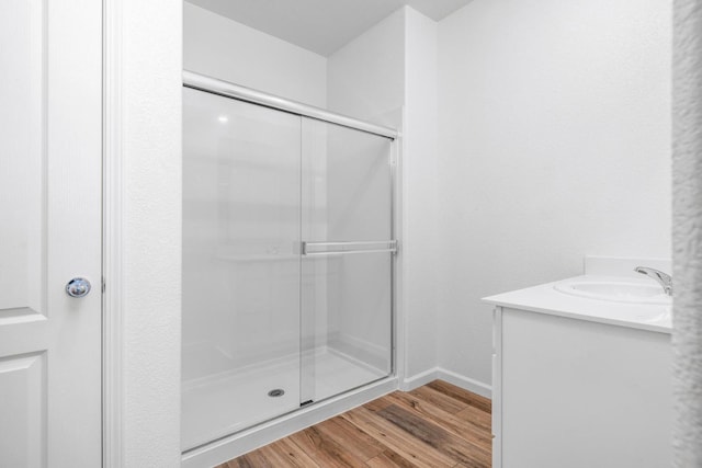 bathroom with baseboards, vanity, wood finished floors, and a shower stall