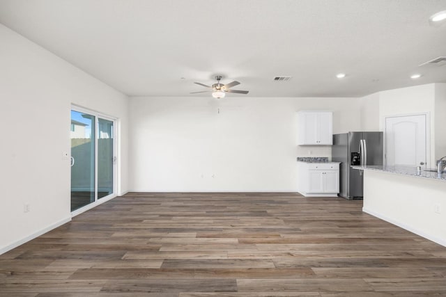 kitchen with wood finished floors, white cabinets, stainless steel fridge with ice dispenser, and open floor plan