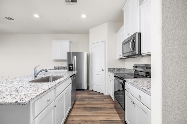 kitchen with visible vents, dark wood finished floors, white cabinets, stainless steel appliances, and a sink