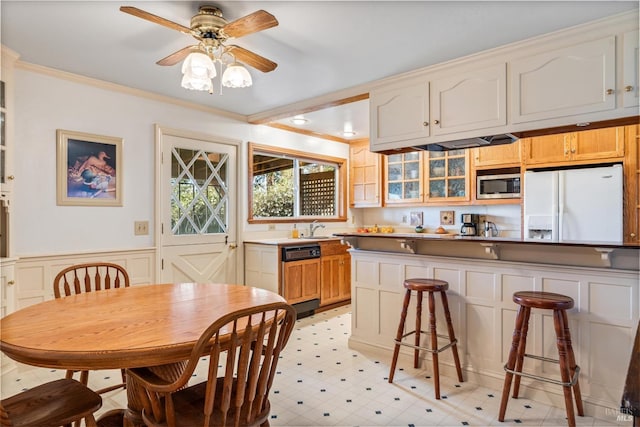 kitchen with white refrigerator with ice dispenser, crown molding, stainless steel microwave, paneled dishwasher, and wainscoting