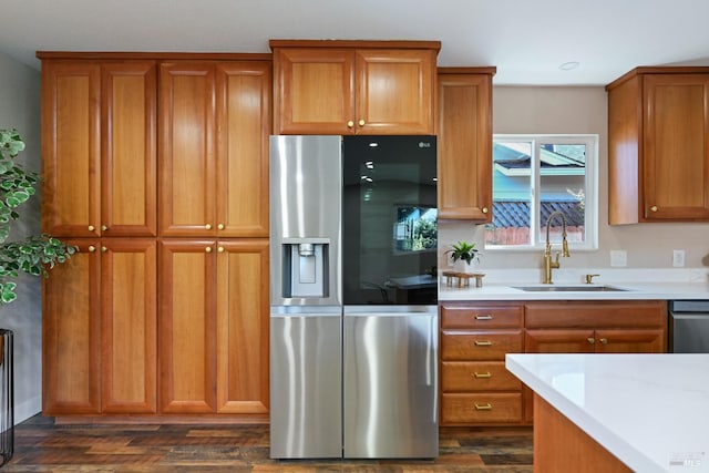 kitchen featuring appliances with stainless steel finishes, brown cabinets, a sink, and dark wood-type flooring