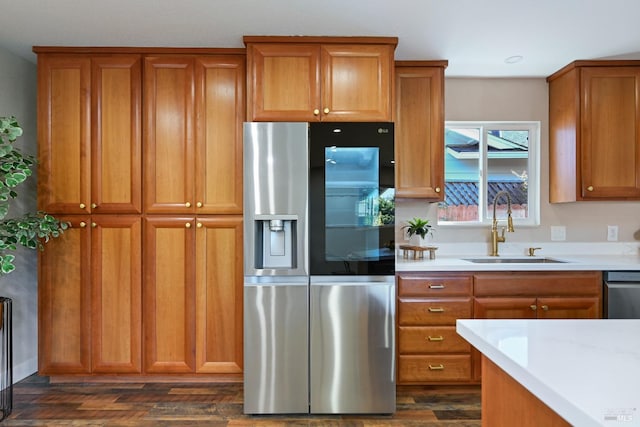 kitchen with stainless steel appliances, brown cabinets, a sink, and dark wood-style floors