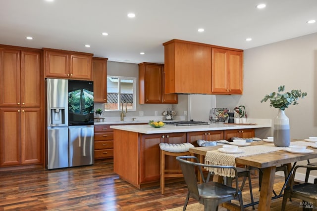 kitchen with dark wood-style floors, light countertops, stainless steel fridge, and brown cabinets