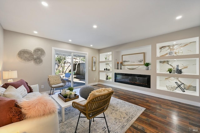 living area featuring baseboards, built in features, a glass covered fireplace, wood finished floors, and recessed lighting