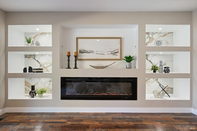 room details with wood finished floors, visible vents, baseboards, built in features, and a glass covered fireplace