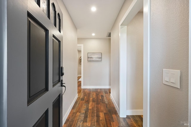 hall featuring recessed lighting, dark wood finished floors, visible vents, and baseboards