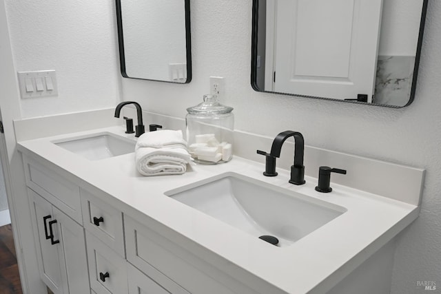 full bathroom with a textured wall, double vanity, and a sink