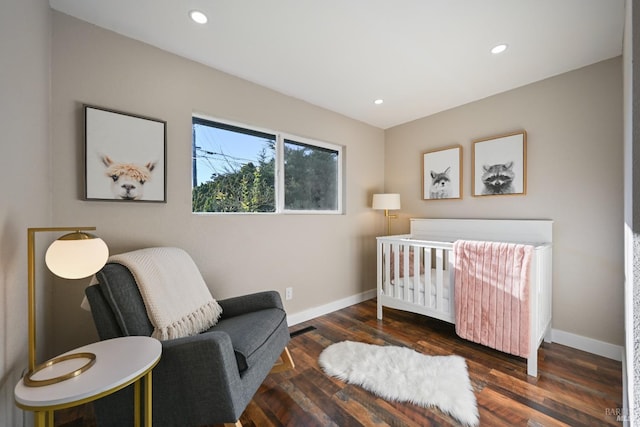 bedroom featuring recessed lighting, a crib, baseboards, and wood finished floors