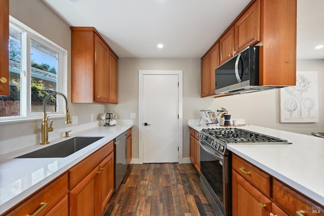 kitchen featuring light countertops, appliances with stainless steel finishes, brown cabinetry, and a sink