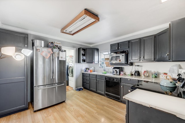 kitchen featuring light wood-style floors, ornamental molding, light countertops, black appliances, and a sink