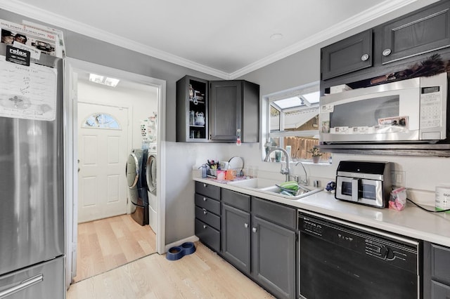 kitchen with black dishwasher, white microwave, freestanding refrigerator, separate washer and dryer, and a sink