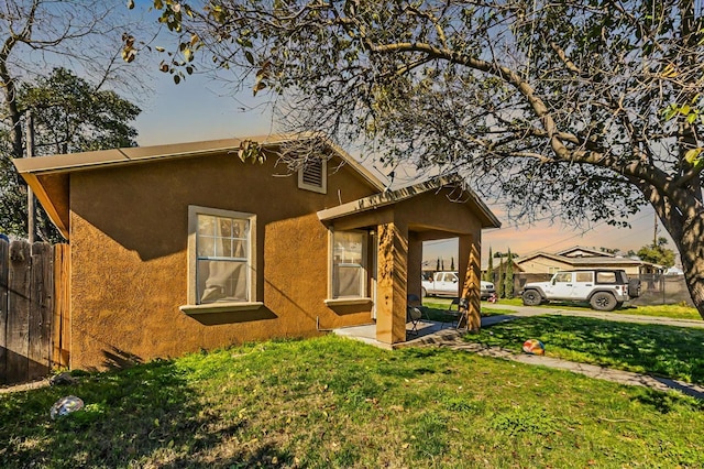 exterior space with a front yard, fence, and stucco siding