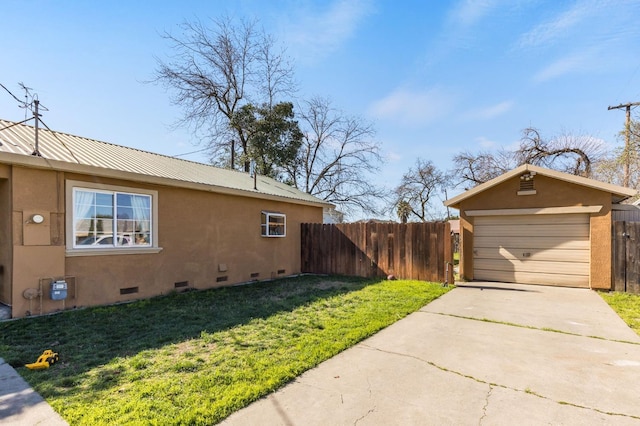 view of side of property featuring metal roof, a yard, concrete driveway, crawl space, and stucco siding