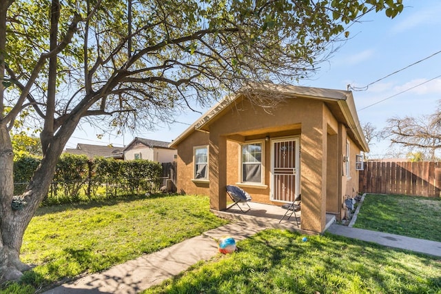 bungalow-style home featuring a front yard, fence, and stucco siding