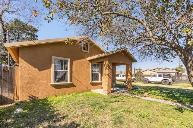 view of front facade featuring a front yard, fence, and stucco siding