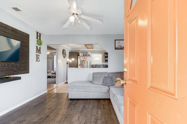 living area with visible vents, ceiling fan, baseboards, and wood finished floors