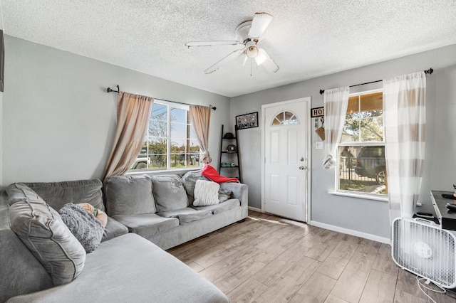 living room featuring a textured ceiling, wood finished floors, a ceiling fan, and baseboards