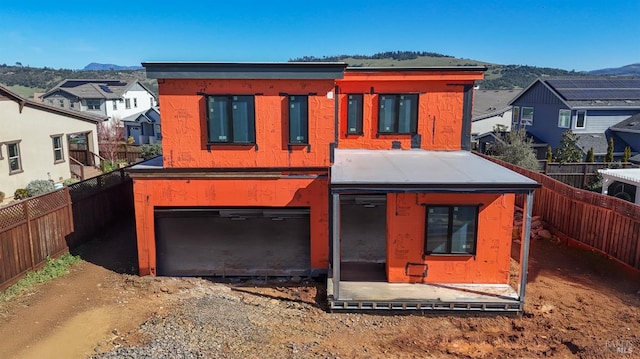 view of front facade with a garage, a fenced backyard, a mountain view, and driveway