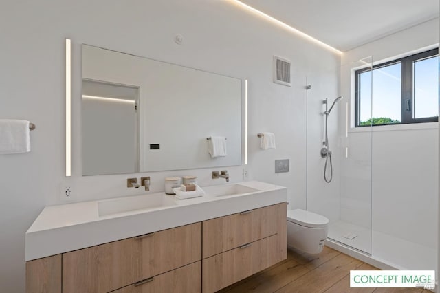 bathroom featuring toilet, wood finished floors, a sink, visible vents, and walk in shower