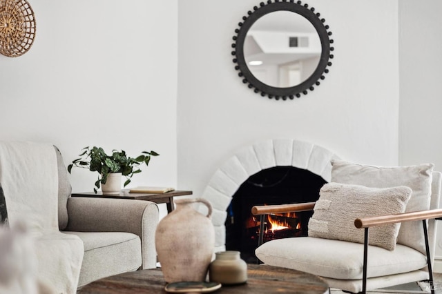 sitting room featuring a lit fireplace, visible vents, and wood finished floors