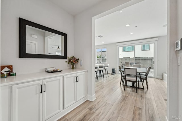 hallway featuring visible vents, recessed lighting, light wood-style flooring, and baseboards