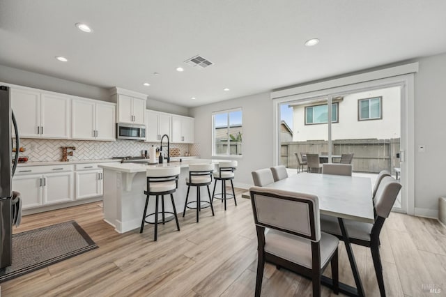 kitchen with light wood-style floors, white cabinets, light countertops, appliances with stainless steel finishes, and tasteful backsplash