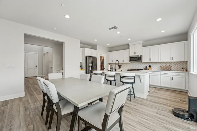 dining space featuring light wood-style floors, baseboards, visible vents, and recessed lighting